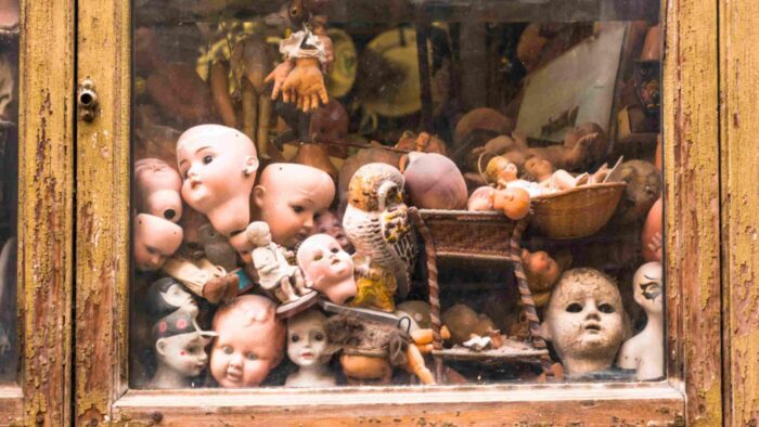 Puppenköpfe in einer Glasvitrine aufgestapelt.